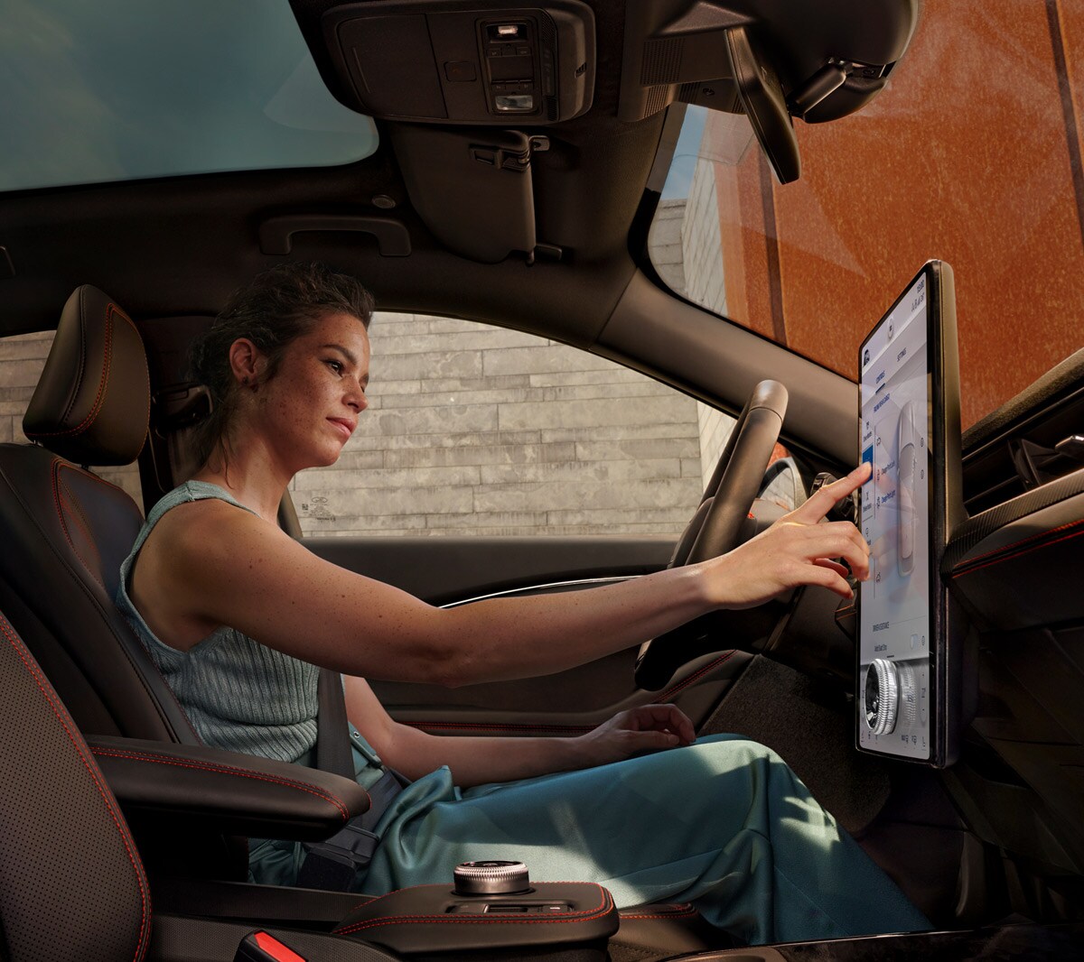 Ford Mustang Mach-E Innenraum. Fahrerin benutzt Ford SYNC 4A Touchscreen 