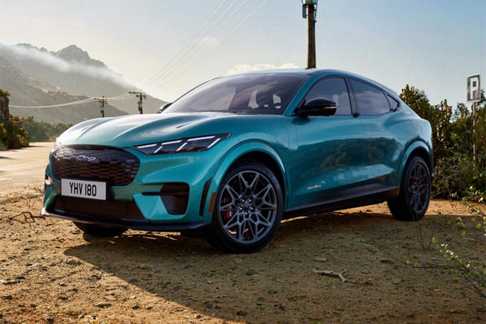 : Ford Mustang Mach-E GT in Blau. Dreiviertelansicht, parkt auf einer Bergstraße.