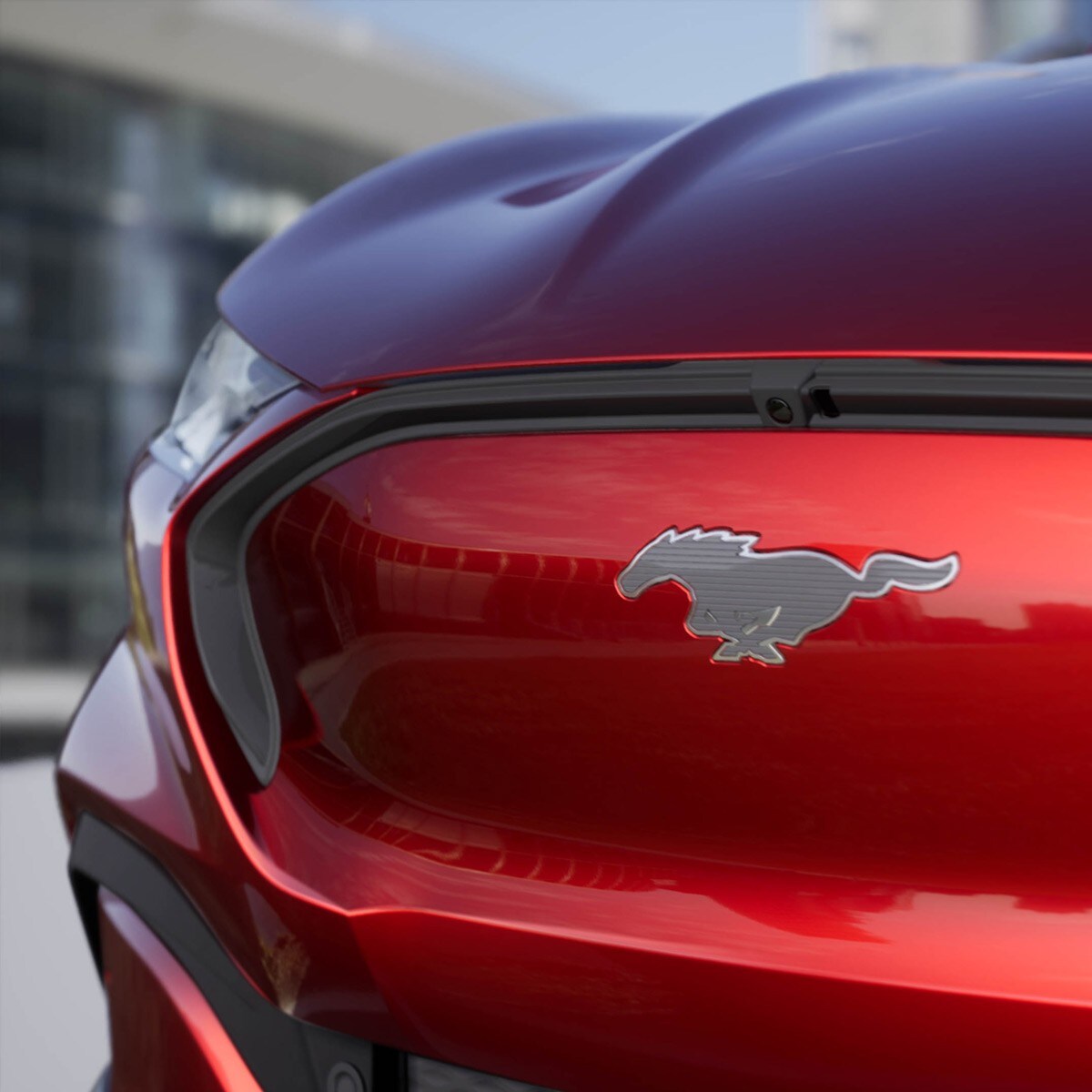 Ford Mustang Mach-E in Rot. Detailansicht Fahrzeugfront mit silbernen Mustang-Pony