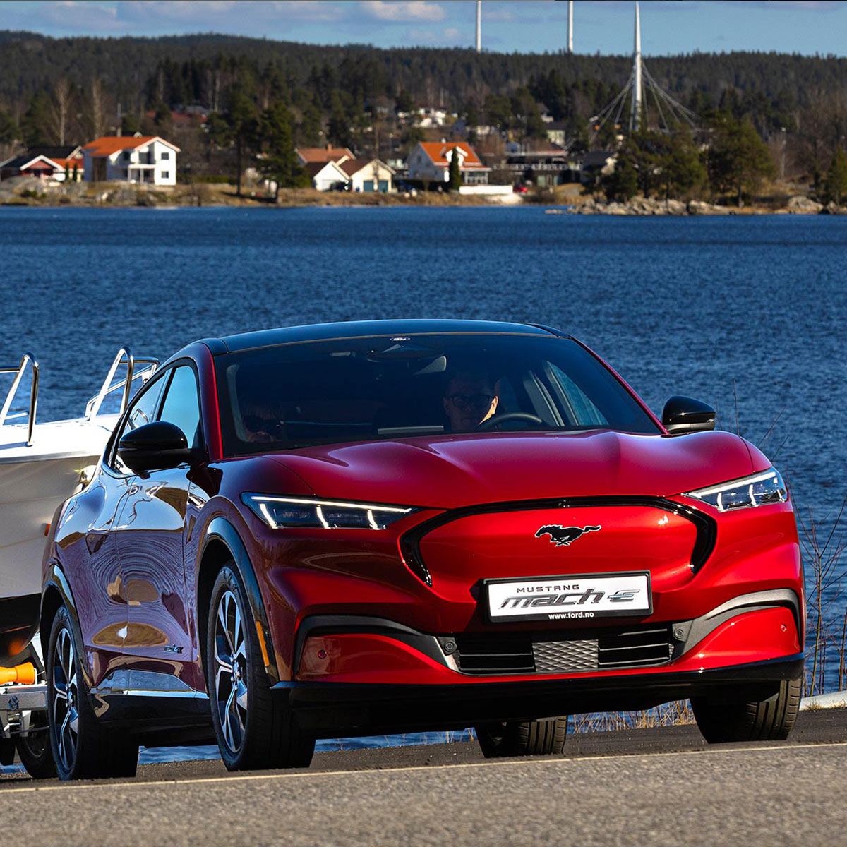 Ford Mustang Mach-E in Rot. Frontansicht, zieht Boot auf einem Anhänger
