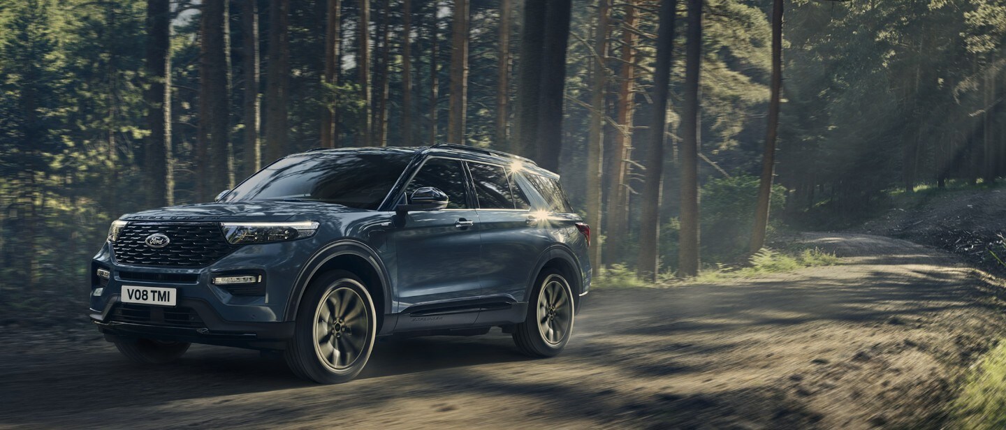 Ford Explorer in Blau. Dreiviertelansicht, fährt in einem Wald