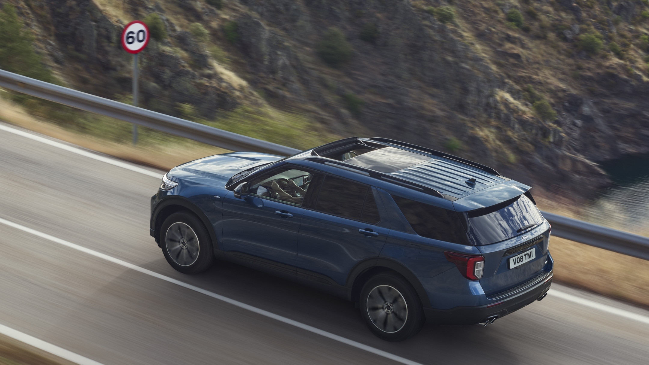 Ford Explorer Plug-in-Hybrid in Blau. Dreiviertelansicht von hinten, bergauf fahrend auf einer Straße in den Bergen