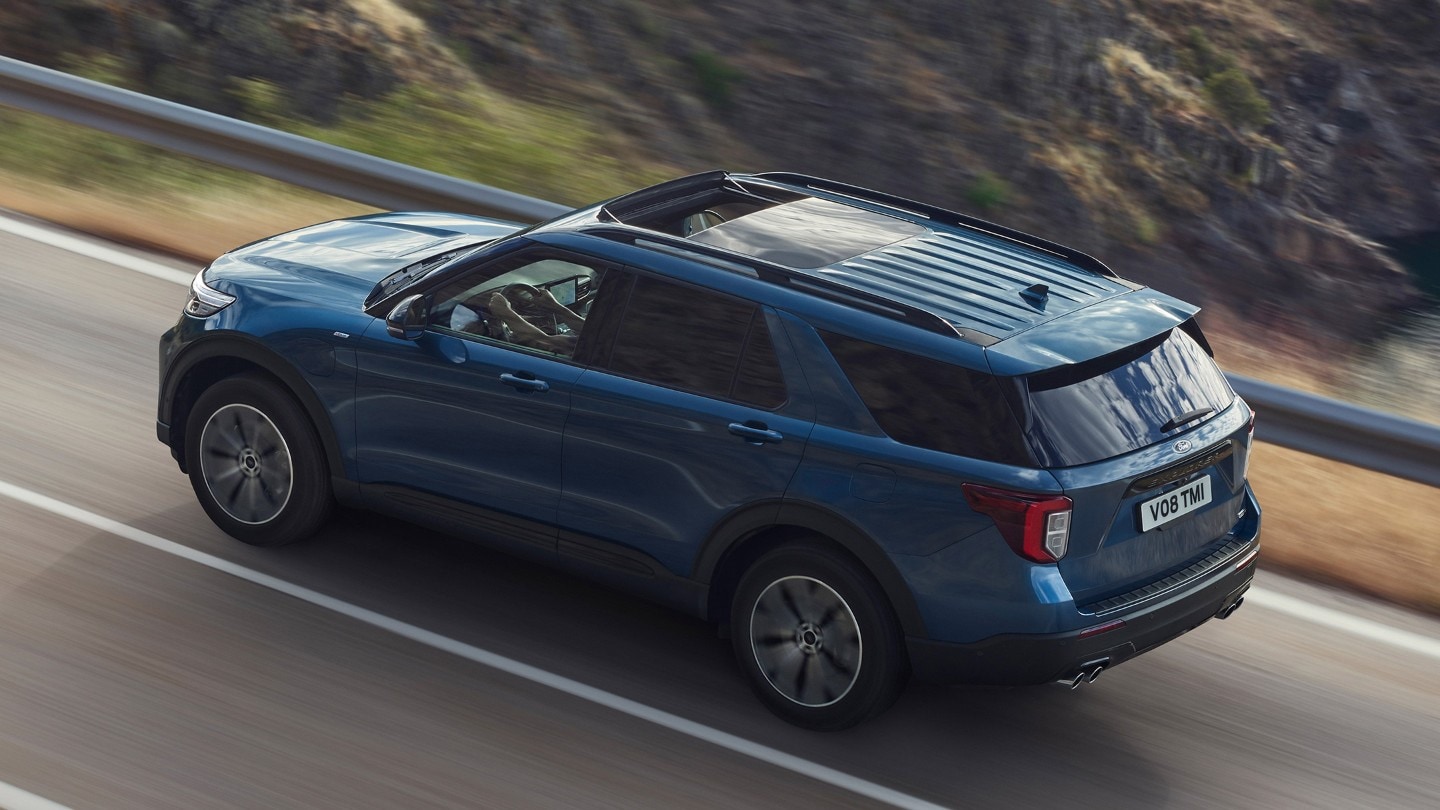 Ford Explorer Plug-in-Hybrid in Blau. Dreiviertelansicht von hinten, bergauf fahrend auf einer Straße in den Bergen