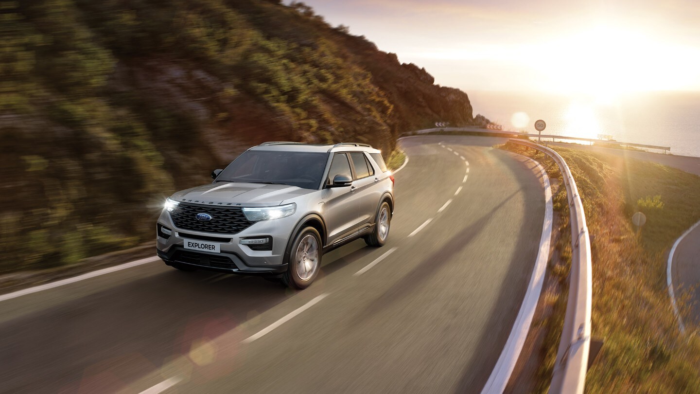 Ford Explorer Plug-in-Hybrid in Silber. Dreiviertelansicht von vorne, fahrend auf einer kurvigen Landstraße