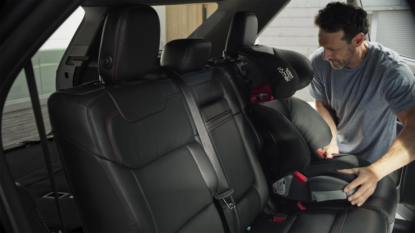 Ford Explorer Plug-in-Hybrid Innenraum. Detailansicht der Rückbank. Mann befestigt einen Kindersitz