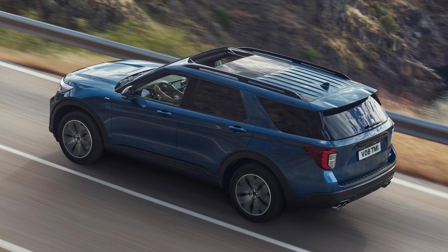 Ford Explorer Plug-in-Hybrid in Blau. Dreiviertelansicht von hinten, bergauf fahrend auf einer Straße in den Bergen