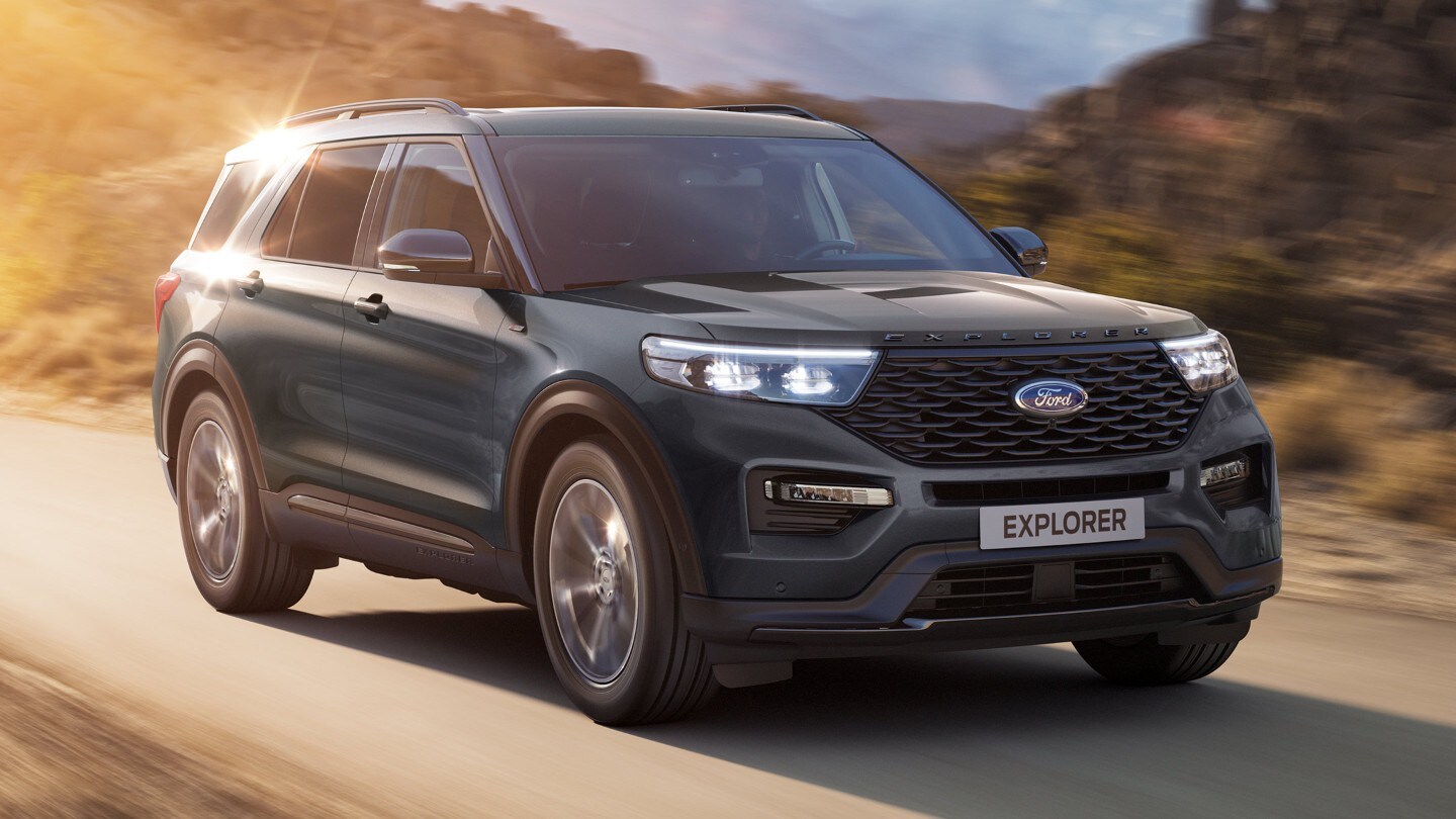 Ford Explorer Plug-in-Hybrid in Blau. Dreiviertelansicht, fahrend auf einer Landstraße mit Bergen im Hintergrund