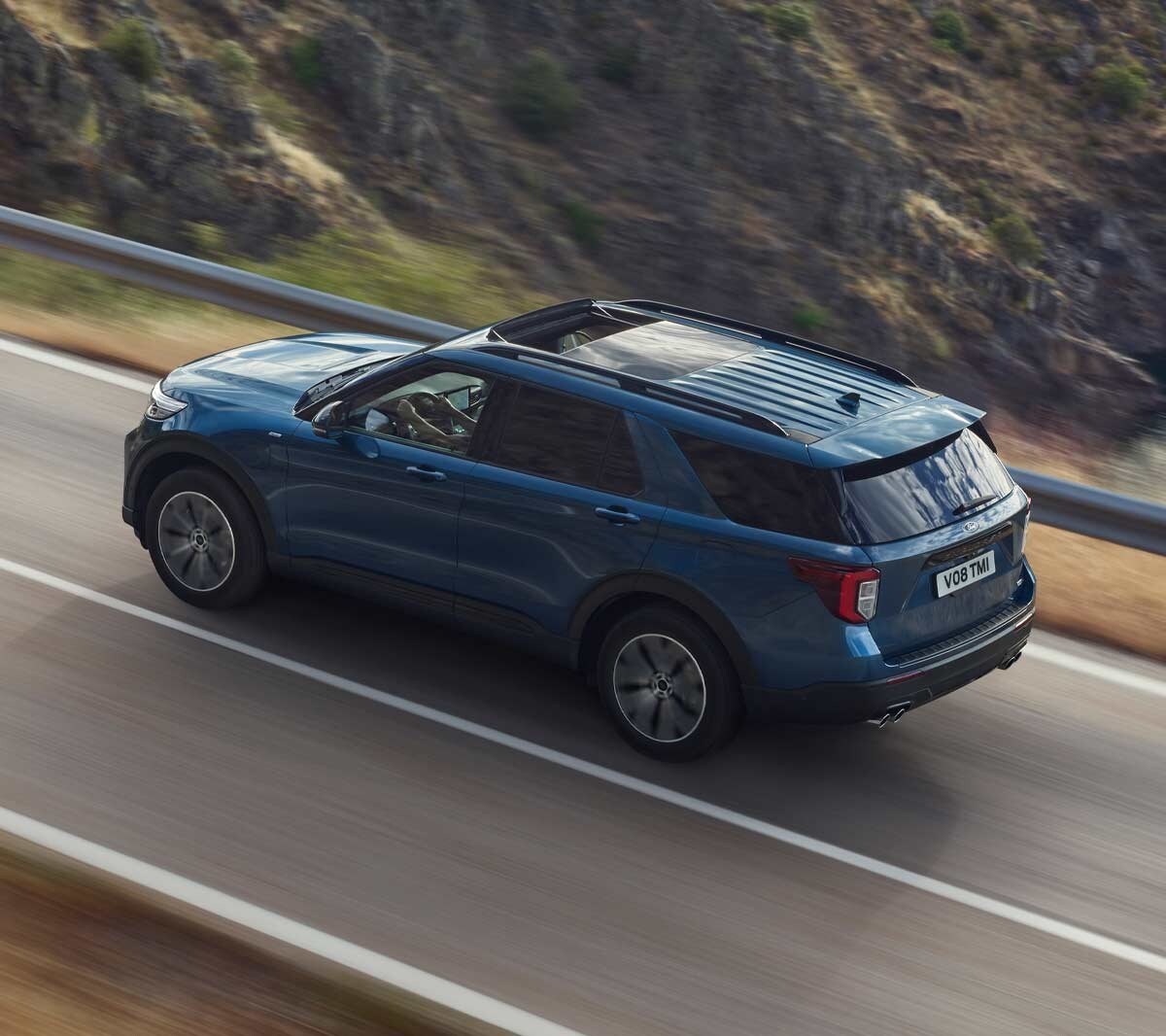 Ford Explorer Plug-in-Hybrid in Blau. Dreiviertelansicht von hinten, bergauf fahrend auf einer Straße in den Bergen