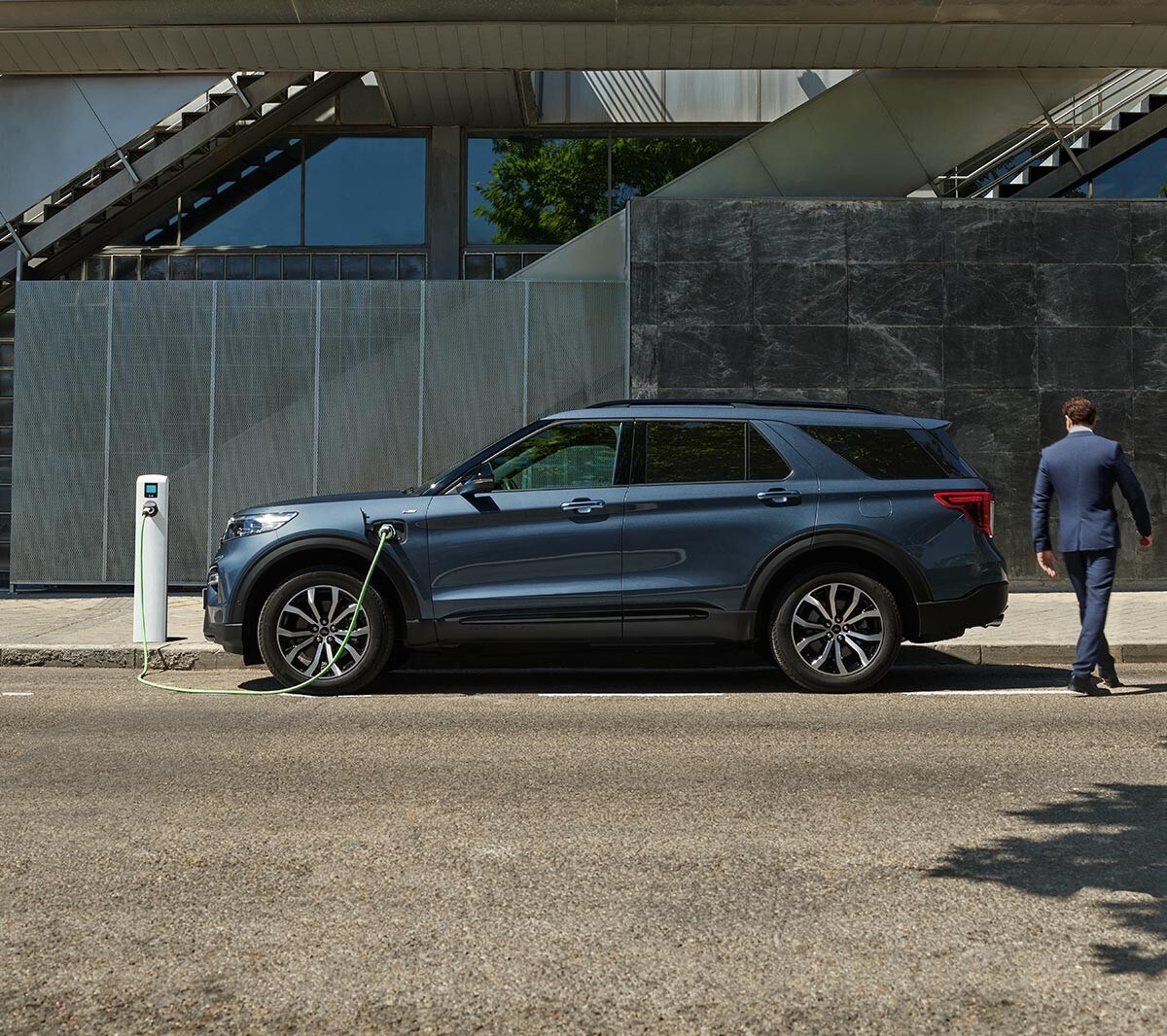 Ford Explorer Plug-in-Hybrid in Blau. Seitenansicht, parkend an einer Ladestation