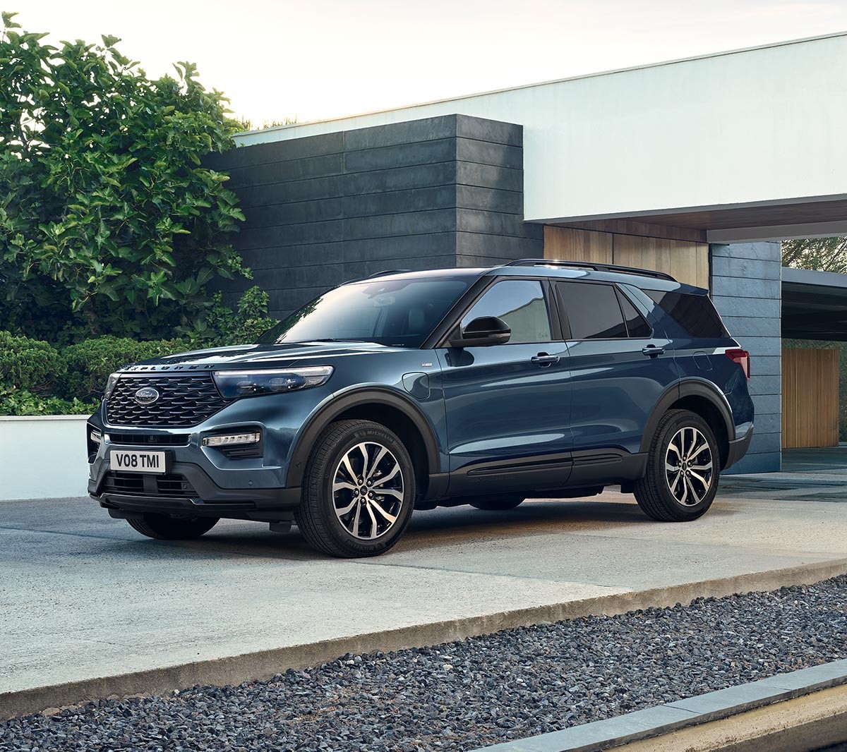 Ford Explorer Plug-in-Hybrid in Blau. Dreiviertelansicht von vorne, parkend vor einem modernen Gebäude