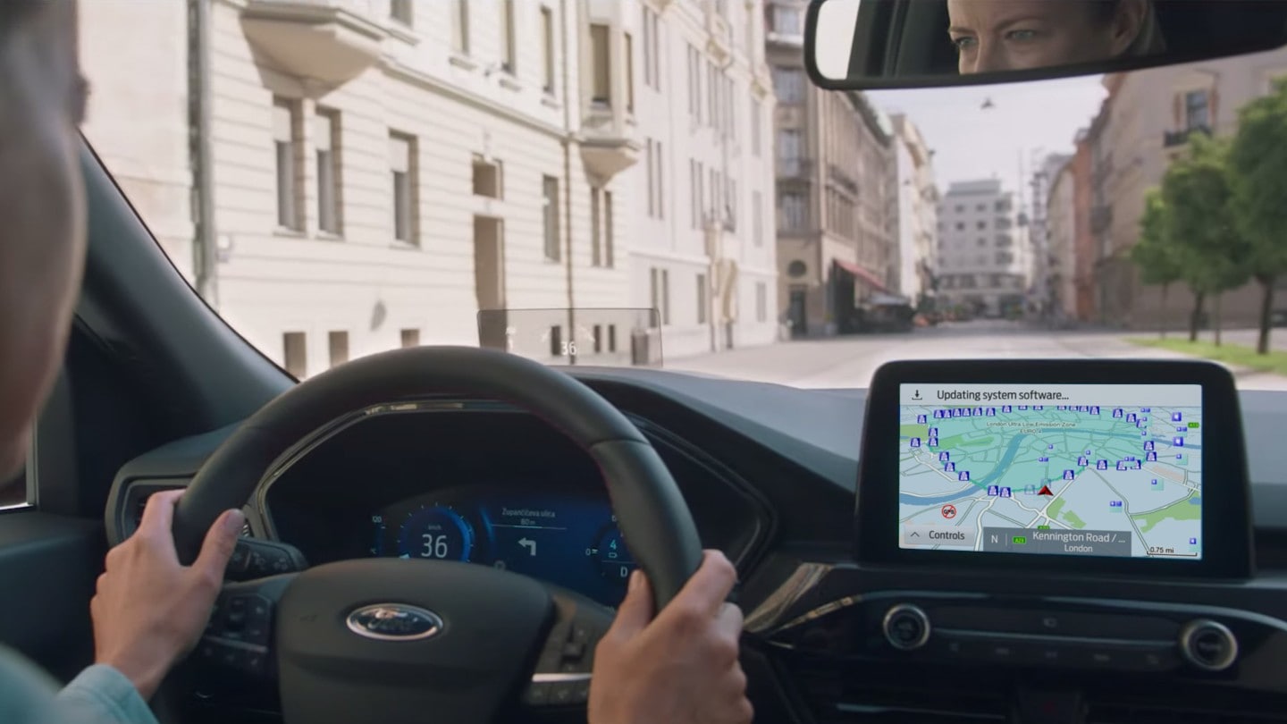 Ford Kuga Innenraumansicht. Blick durch die Windschutzscheibe, Hände des Fahrers am Steuer und Ford SYNC 3-Bildschirm