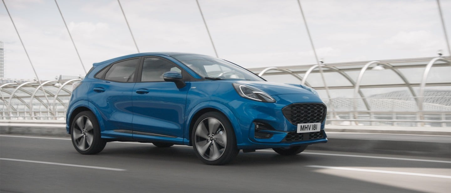 Ford Puma in Blau. Dreiviertelansicht, fährt auf einer Brücke