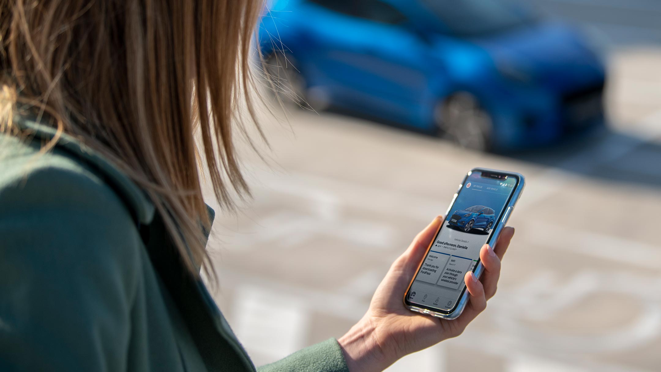 Eine Frau schaut auf ein Smartphone mit geöffneter FordPass App.