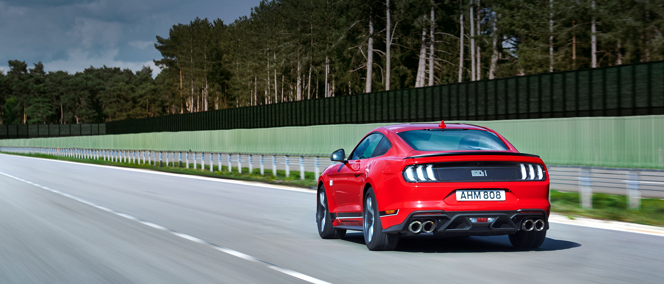 Ford Mach 1 in Rot. Heckansicht, auf Straße fahrend