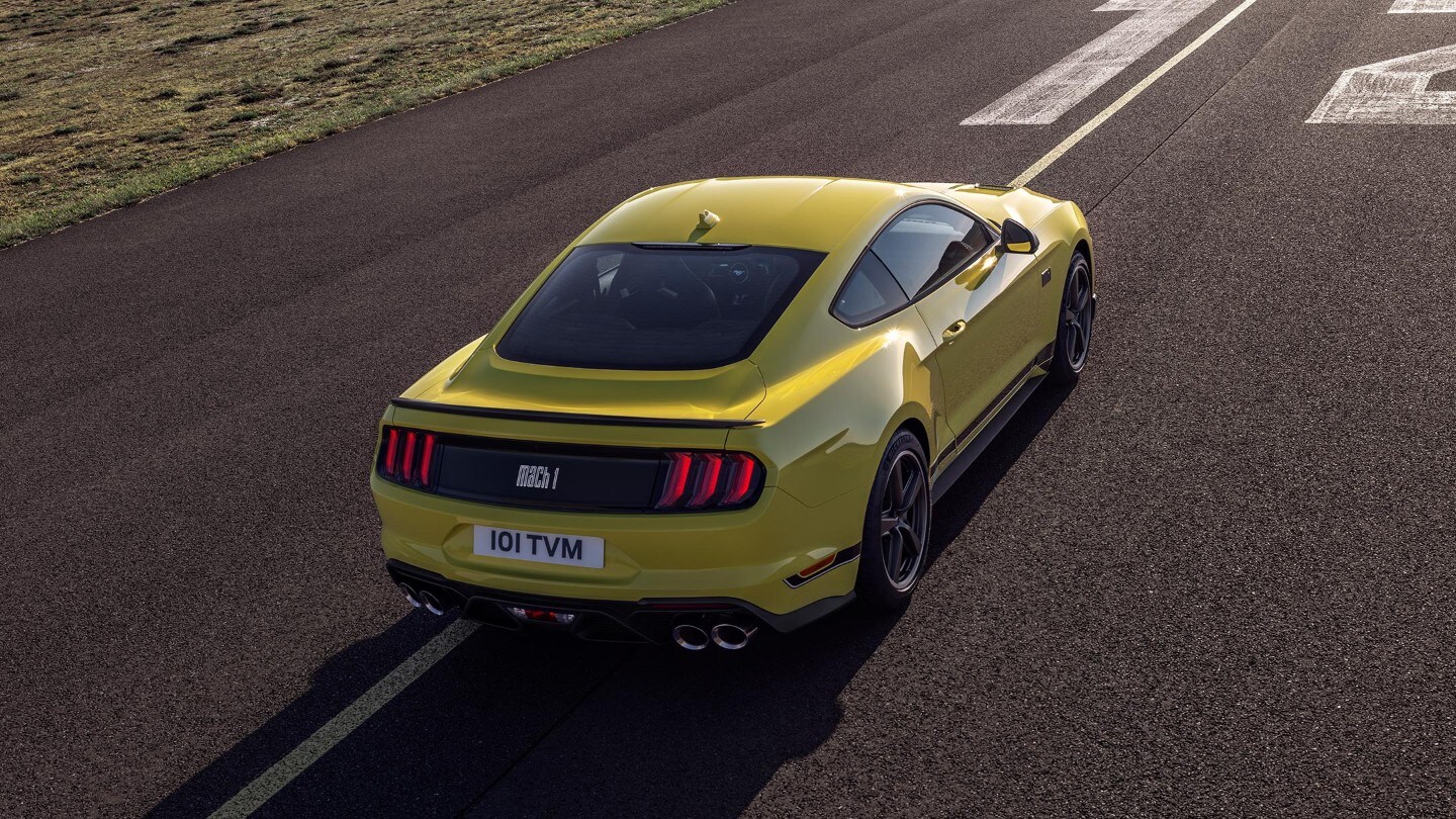 Ford Mustang Mach 1 in Gelb. Dreiviertelansicht von hinten, fahrend auf einer Strecke