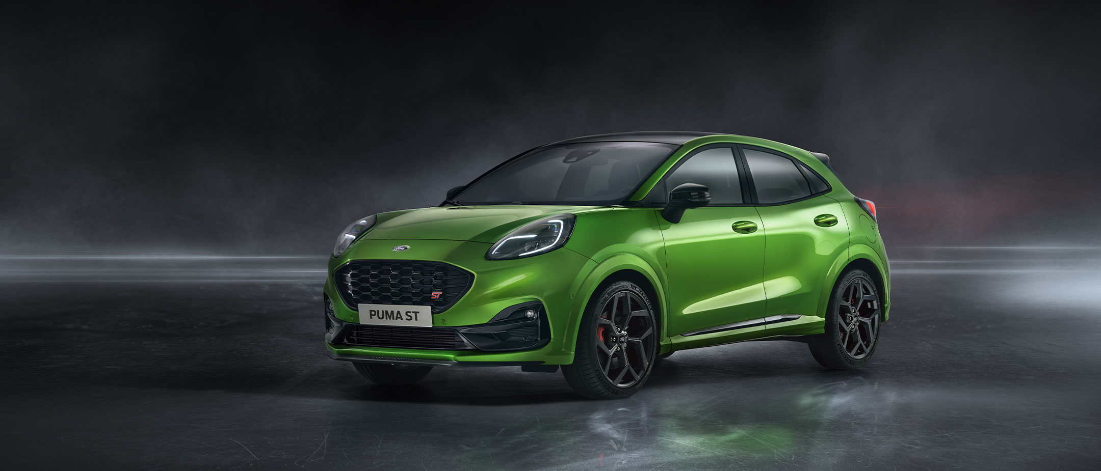 Ford Puma ST in Grün. Dreiviertel-Frontansicht, fahrend auf einer Landstraße