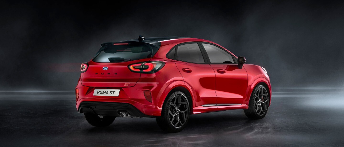 Ford Puma ST in Rot. Dreiviertel-Heckansicht, stehend in einem dunklen Showroom