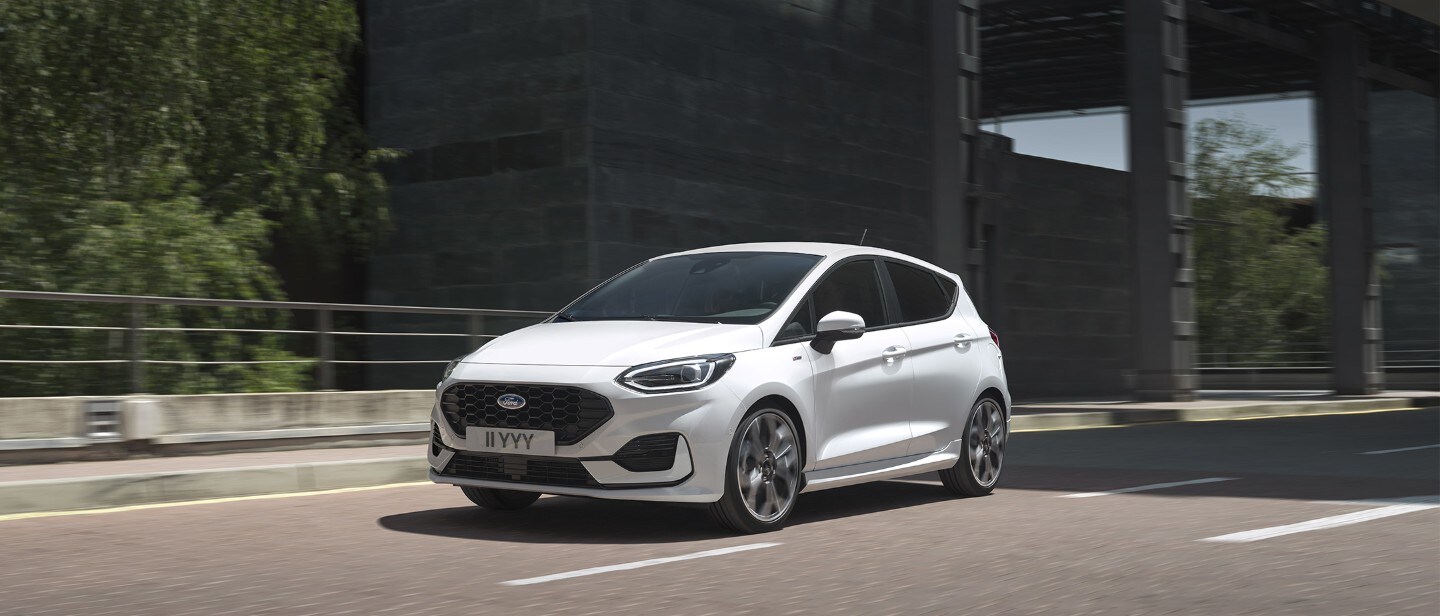 Ford Fiesta in Weiß. Dreiviertelansicht, fährt unter einer Brücke