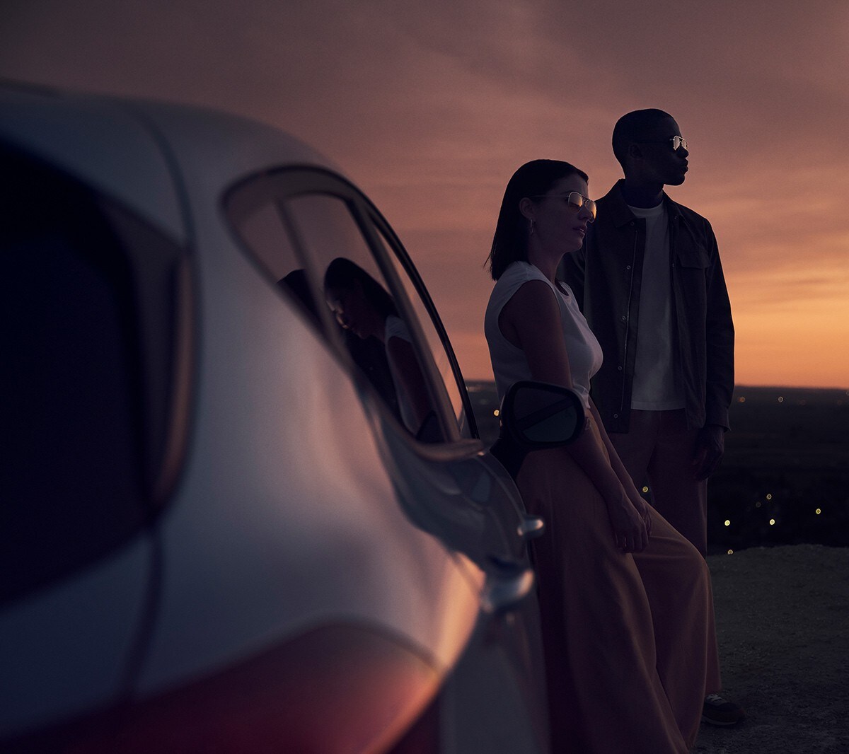 Ford Fiesta in Blau. Heckansicht, im Sonnenuntergang mit zwei Personen im Hintergrund.
