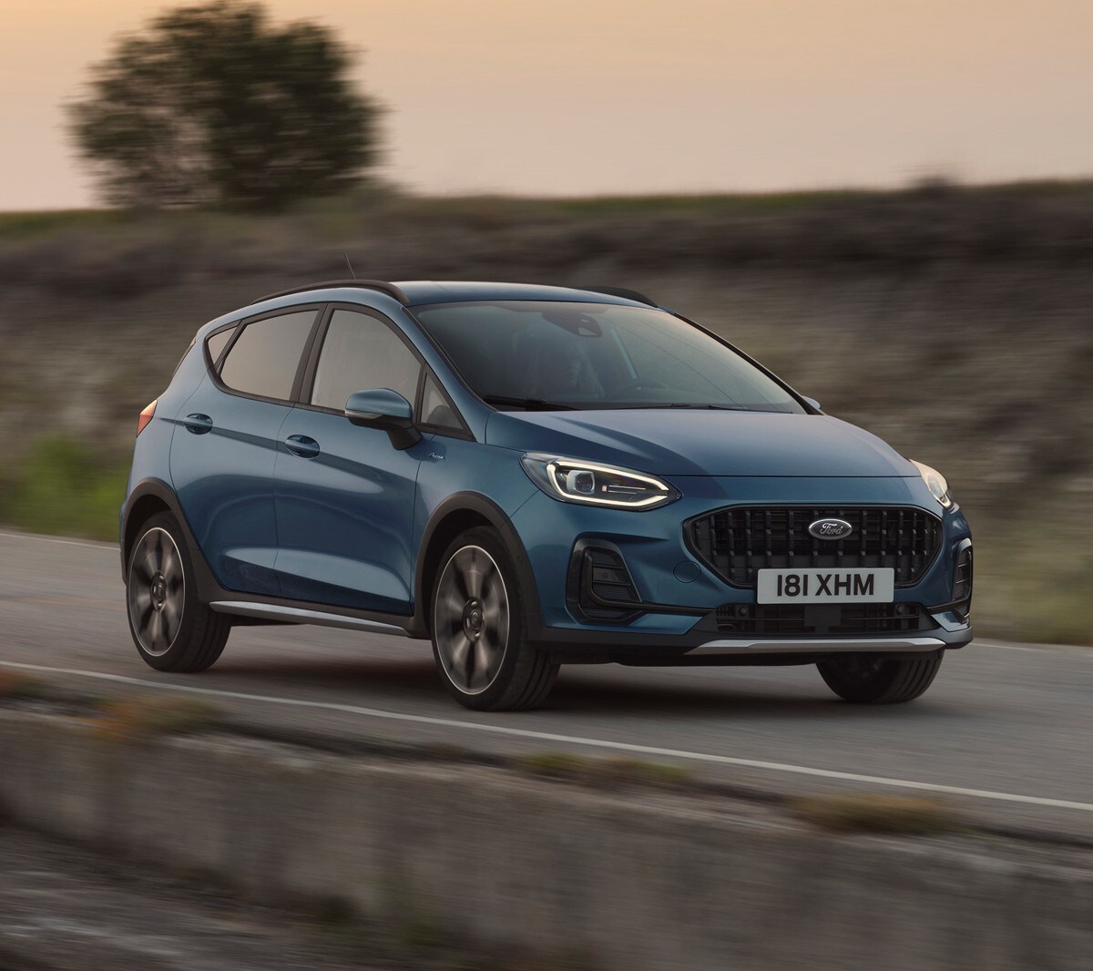 Ford Fiesta in Blau. Dreiviertelansicht, auf einer Straße im Sonnenuntergang fahrend.