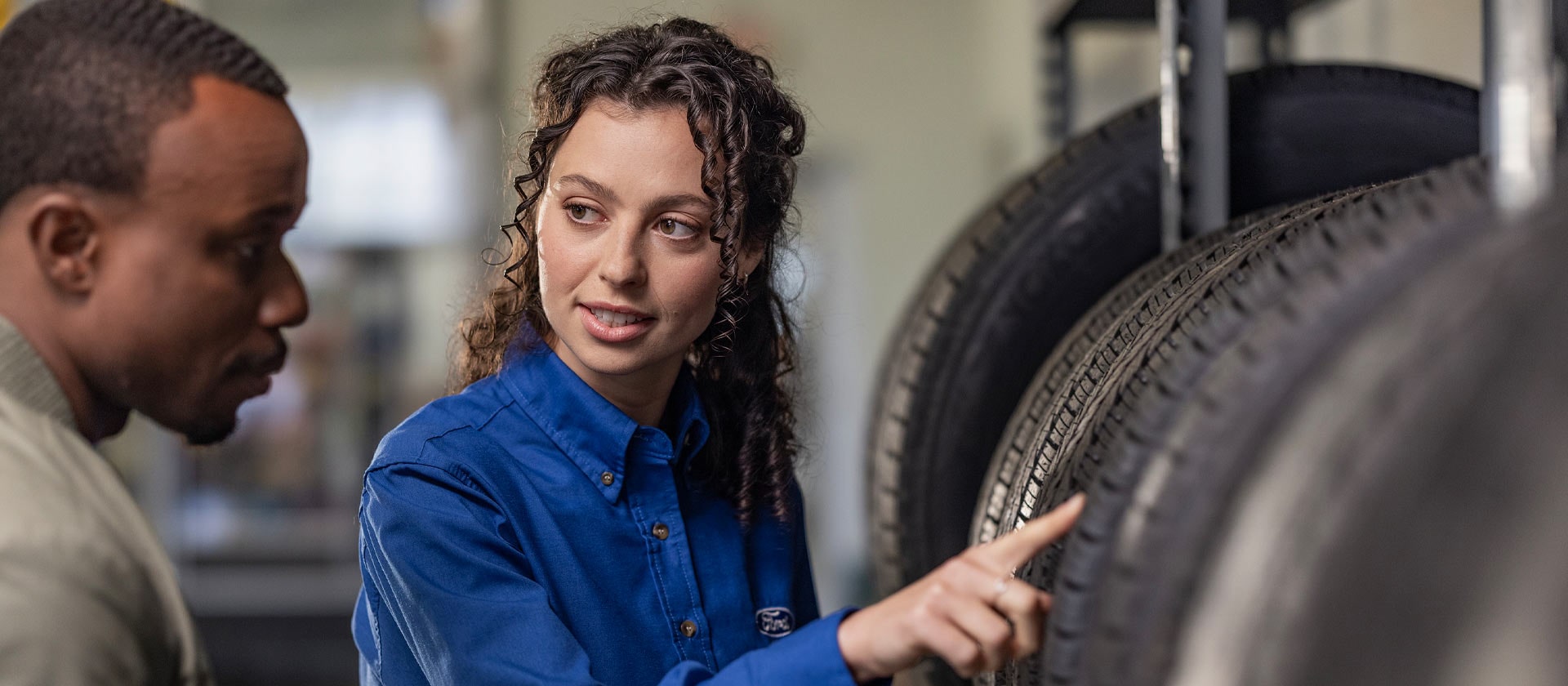 Ford-Servicetechniker berät einen Kunden zu Autoreifen.
