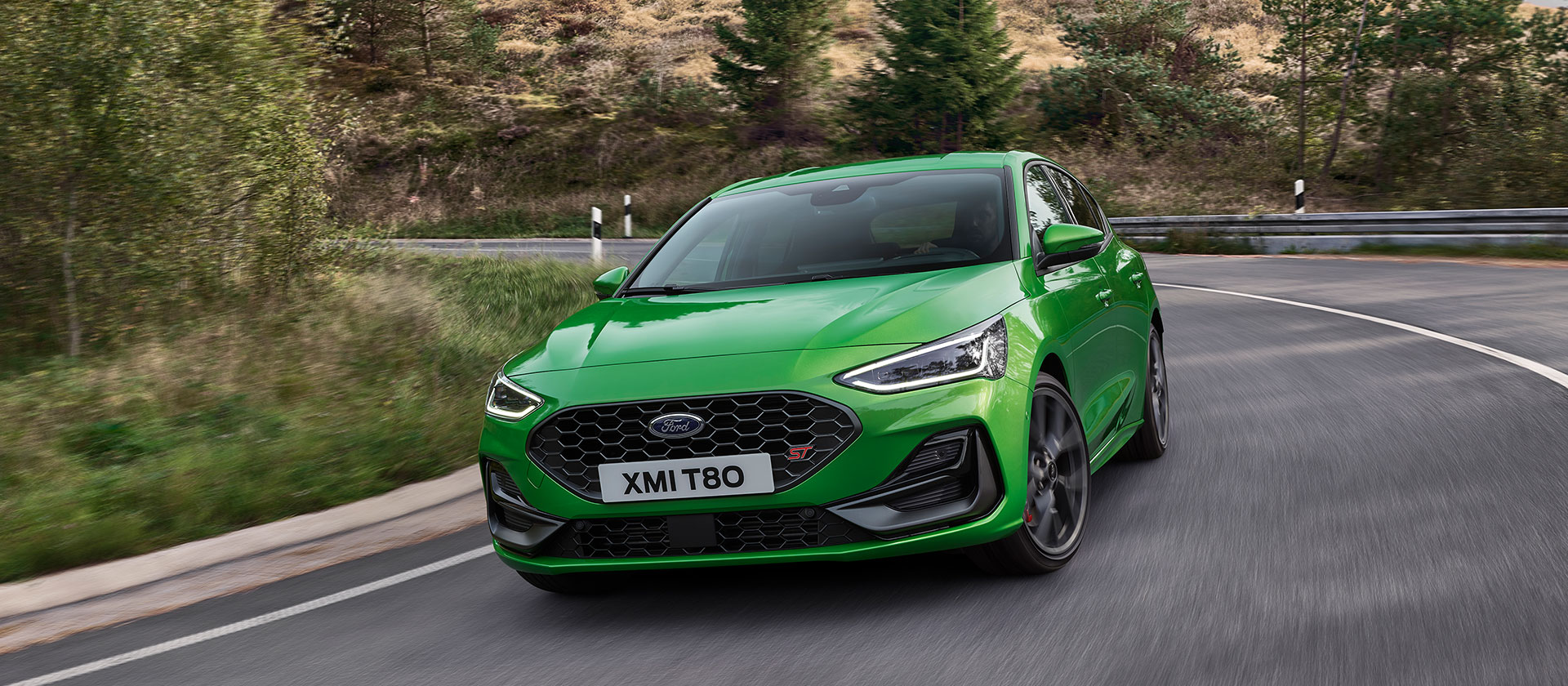 Ford Focus ST in Grün.  Dreiviertelansicht, fahrend in der Kurve.