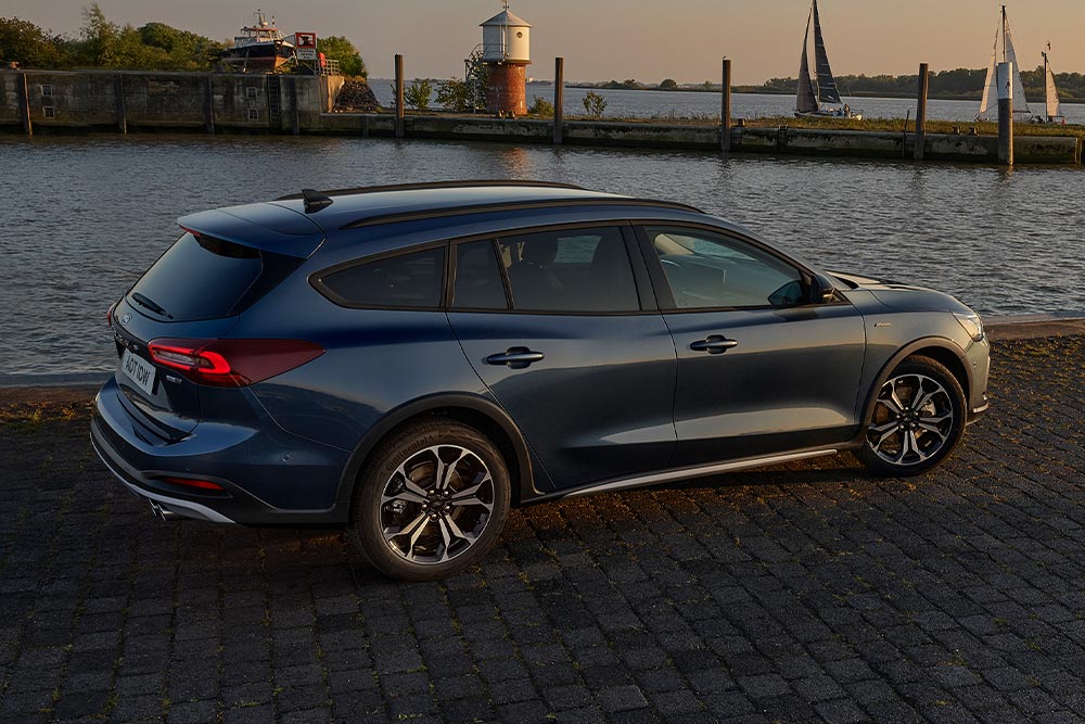Ford Focus Active in Blau. Seitenansicht, vor einem See parkend bei Dämmerung.