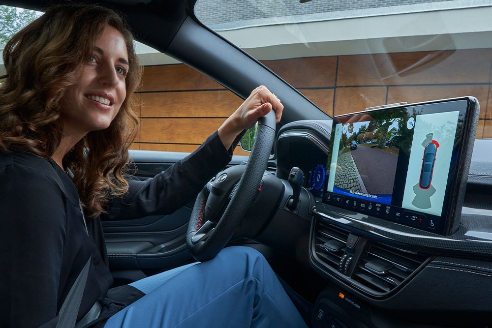 Ford Focus Innenraumansicht. Frau parkt mit Rückfahrkamera aus.