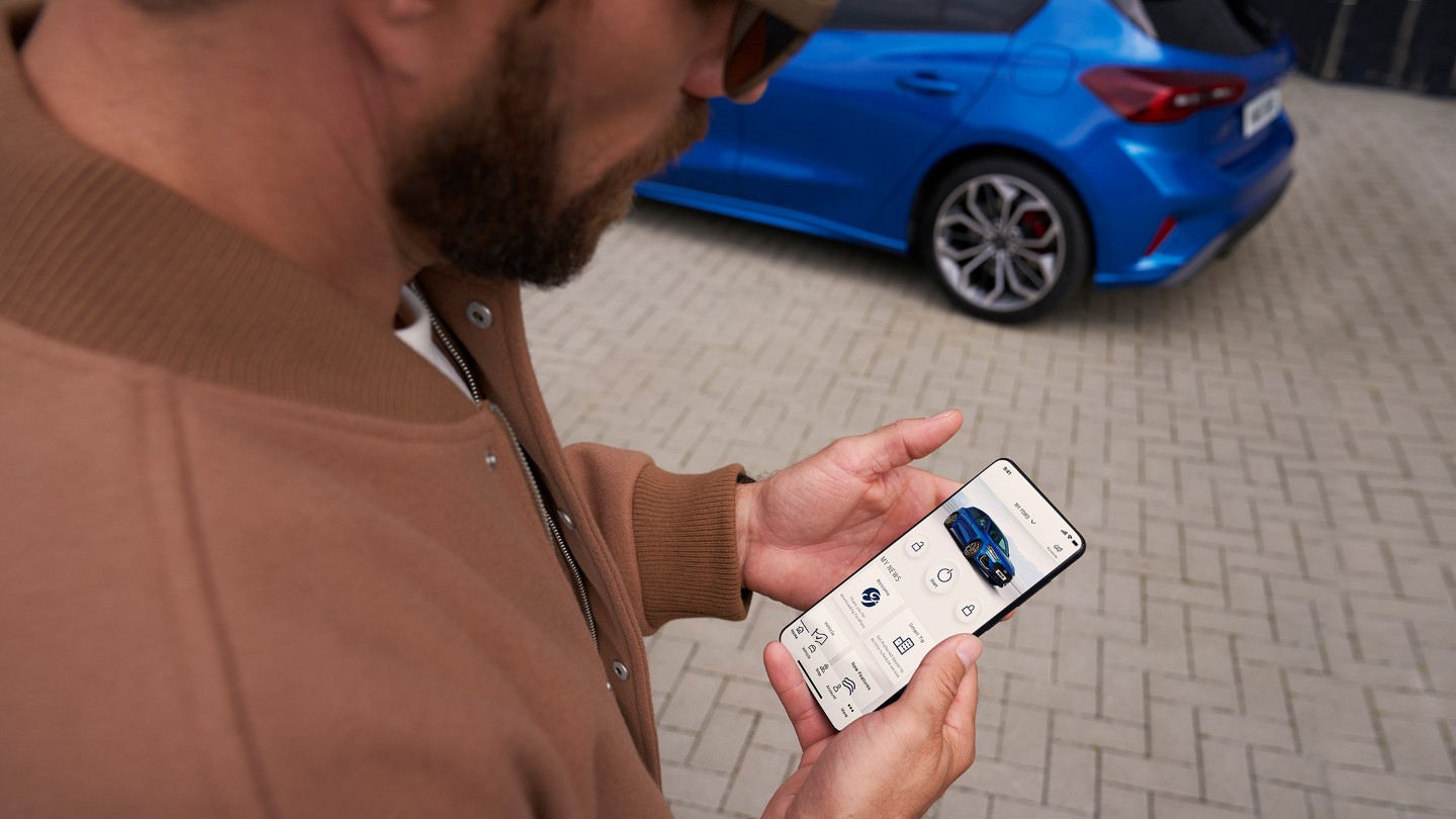 Mann hält Smartphone in der Hand mit geöffneter FordPass App.