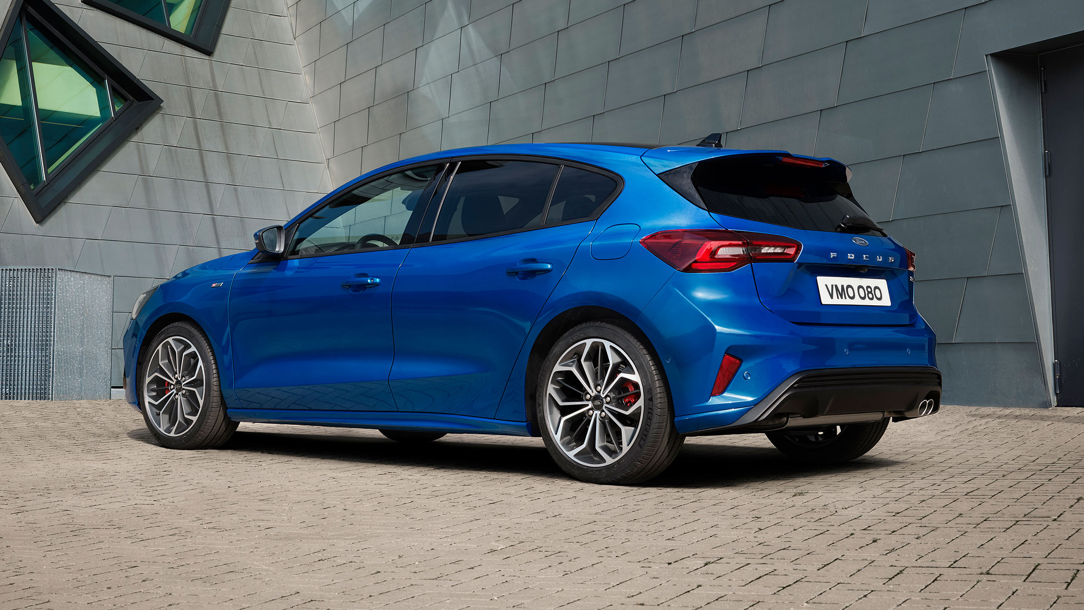 Ford Focus ST-Line in Blau. Heckansicht, vor einem modernen Gebäude parkend.