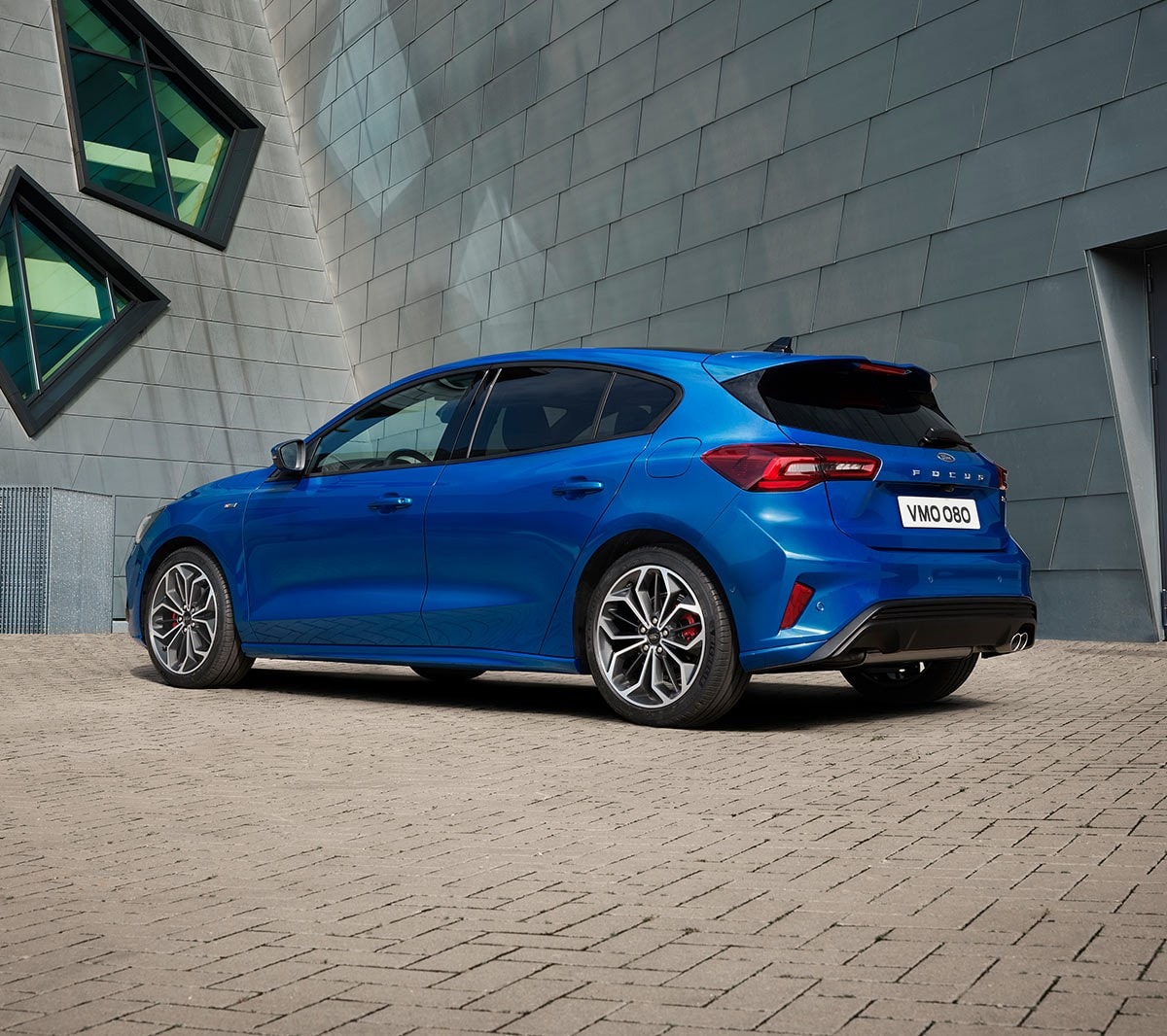 Ford Focus in Blau. Heckansicht, vor einem modernen Gebäude parkend.  