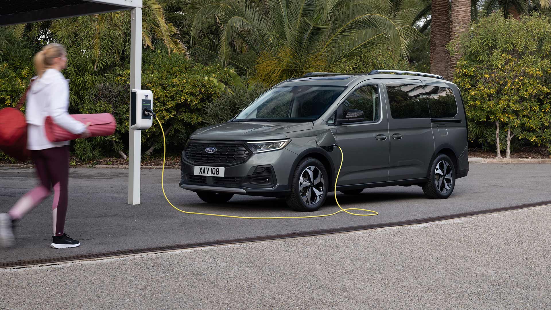 Ford Tourneo Connect in Grau. Dreiviertelansicht, an einer Ladestation angeschlossen.