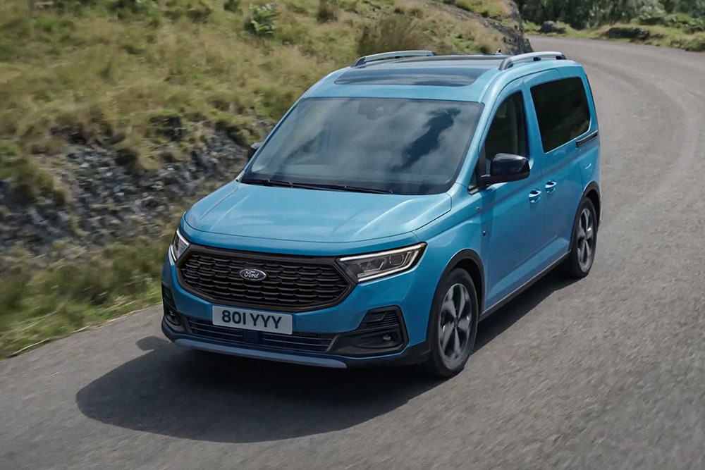 Ford Tourneo Connect in Blau. Dreiviertelansicht, fährt auf Landstraße.