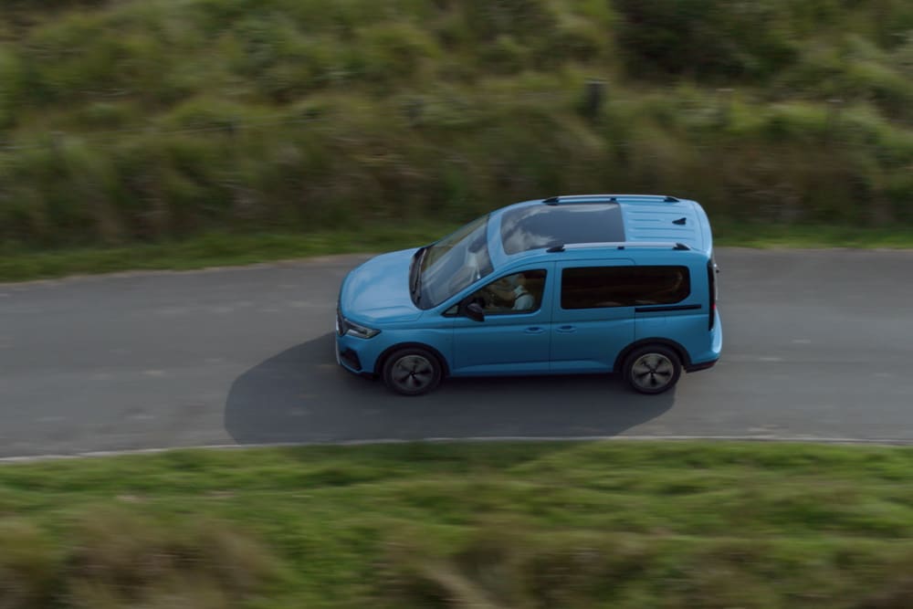 Ford Tourneo Connect in Blau. Vogelperspektive, fahrend auf einer Landstraße.