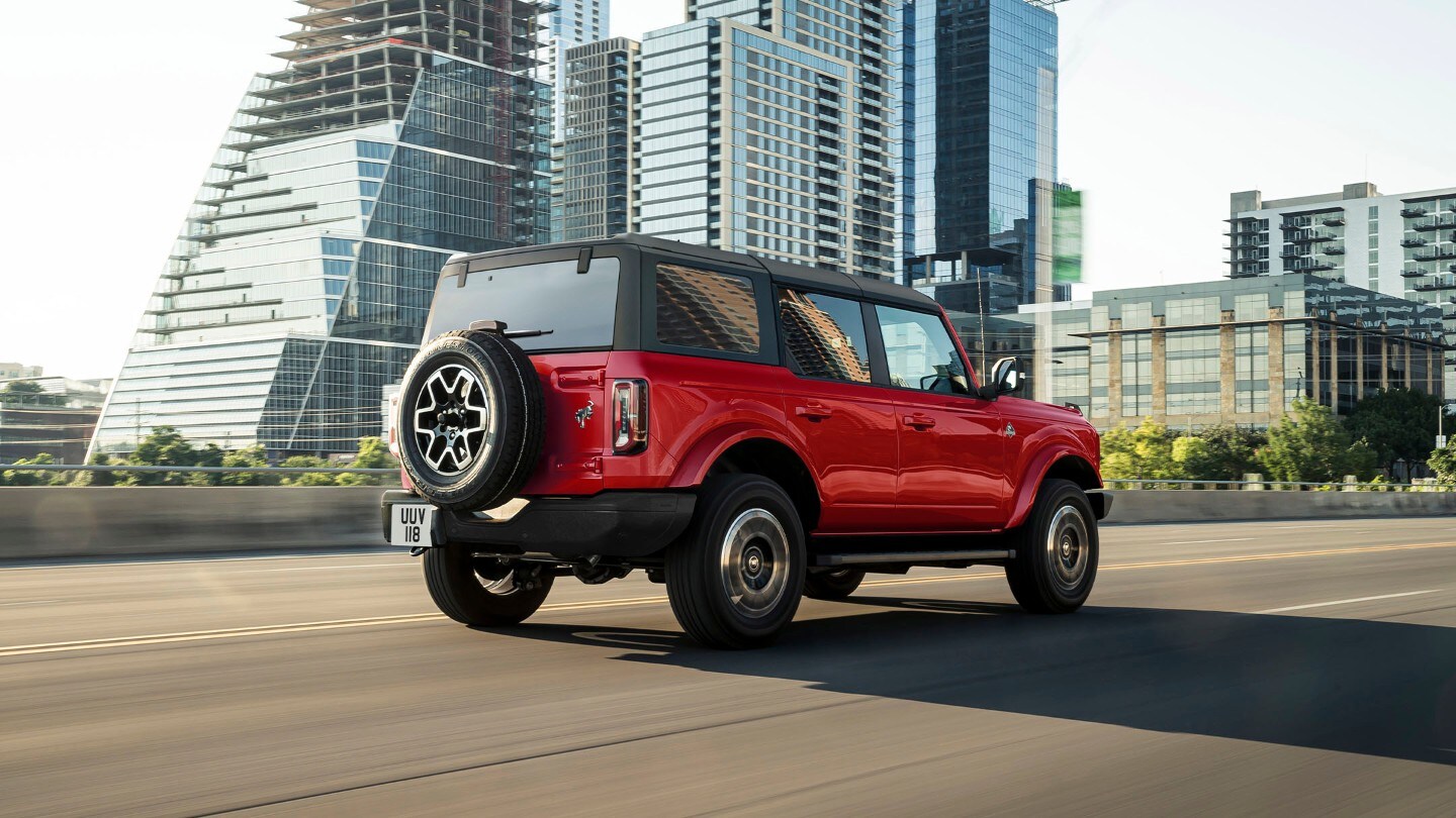 Ford Bronco in Rot. Heckansicht, fahrend durch die Stadt