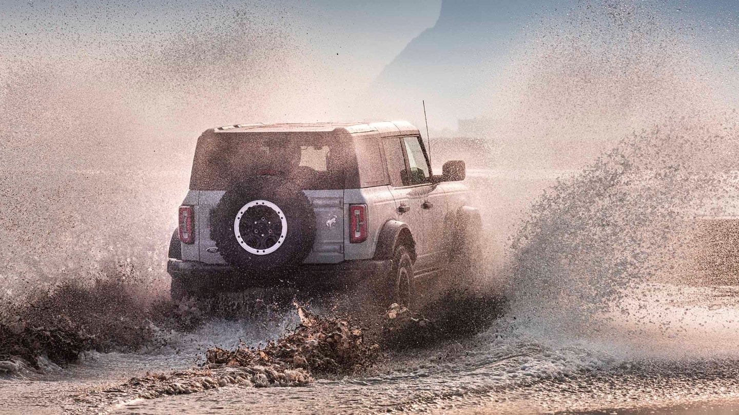 Ford Bronco in Grau. Heckansicht, fährt durch Wasser