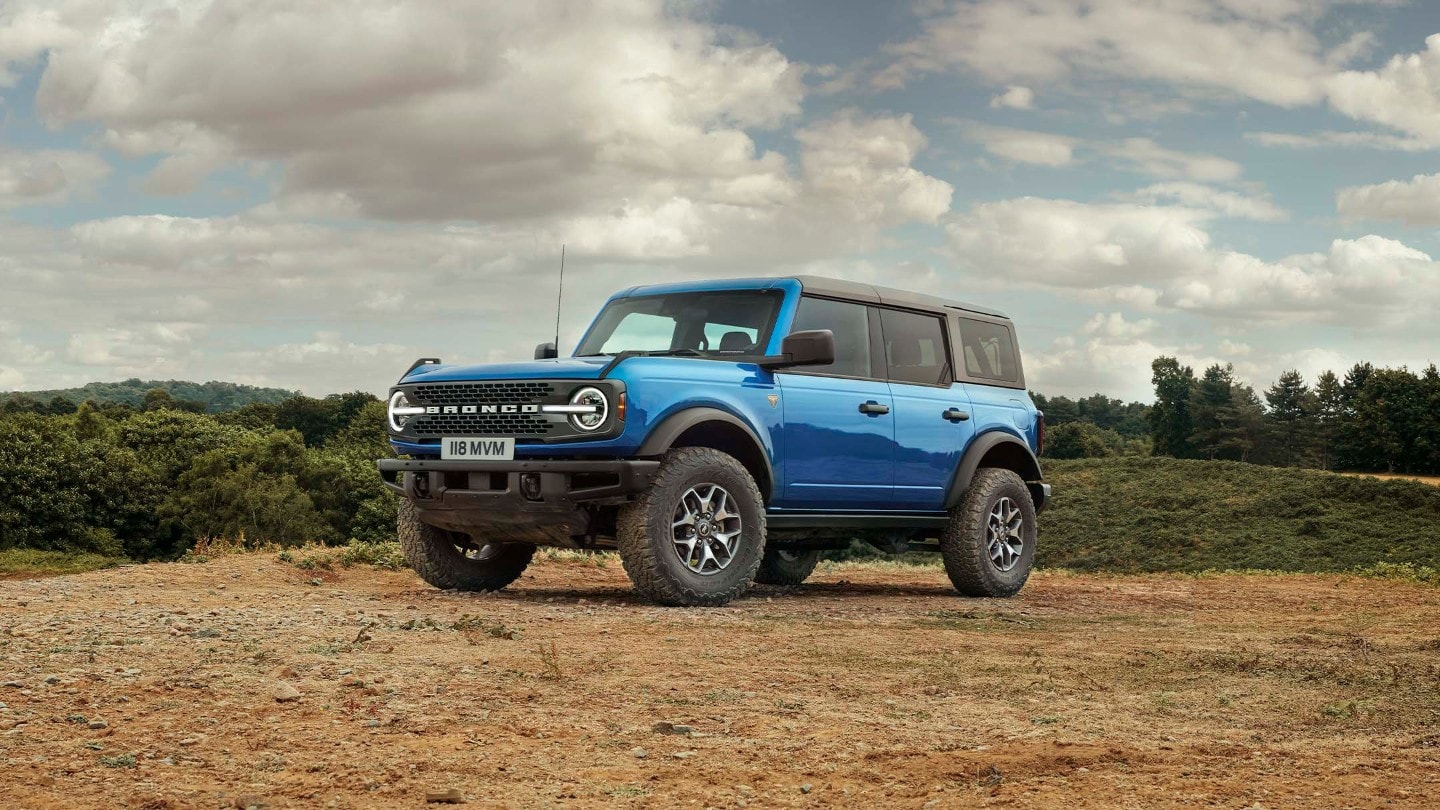 Ford Bronco in Blau. Dreiviertelansicht, stehend auf sandigem Untergrund