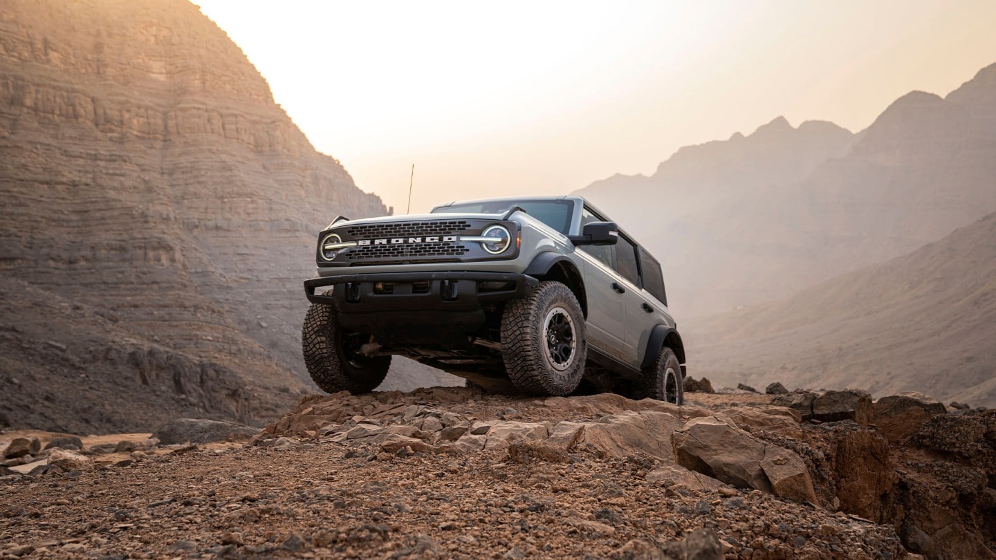 Ford Bronco in Grau. Frontansicht, fahrend durch eine Berglandschaft