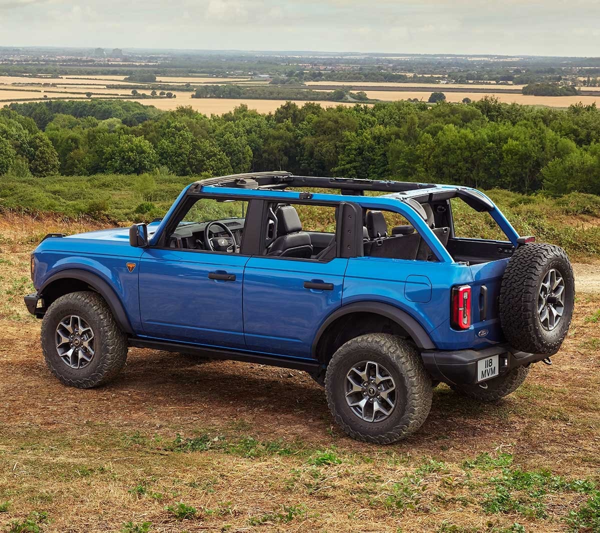 Ford Bronco in Blau. Dreiviertelansicht, fahrend auf sandigem Untergrund