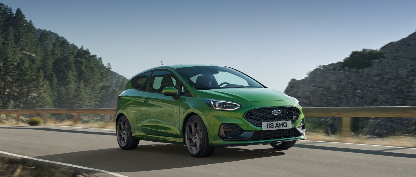Ford Fiesta ST in Grün. Dreiviertelansicht, mit bewaldetem Gebiet im Hintergrund