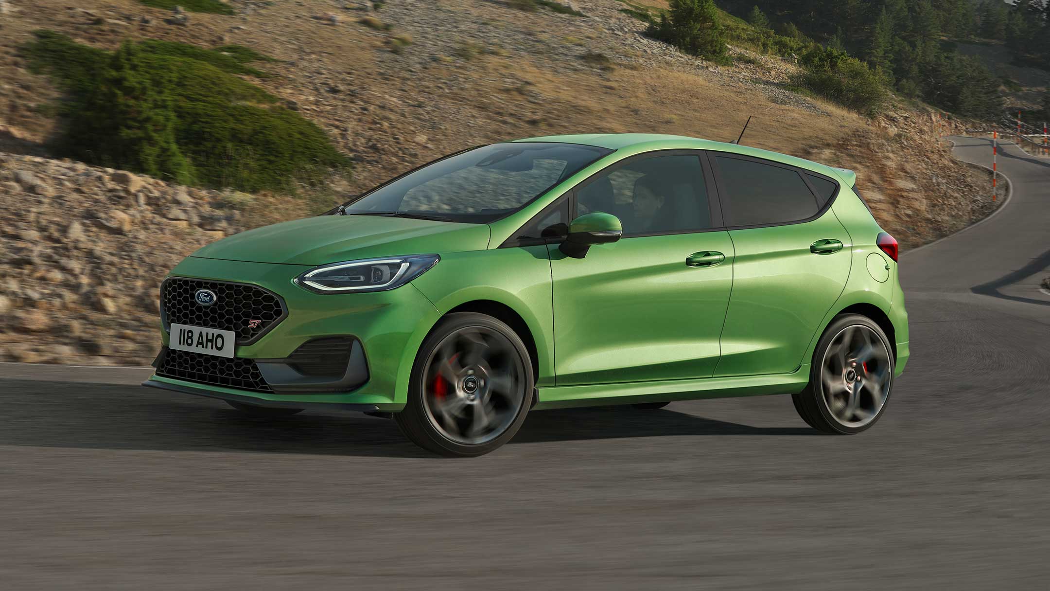 Ford Fiesta ST in Grün. Dreiviertelansicht, auf einer Landstraße fahrend.