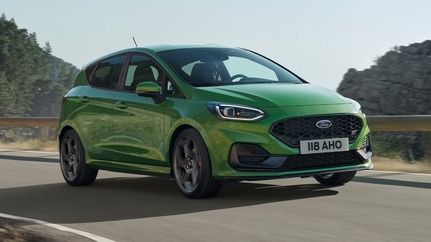 Ford Fiesta ST in Grün. Dreiviertelansicht, auf Straße in den Bergen fahrend.