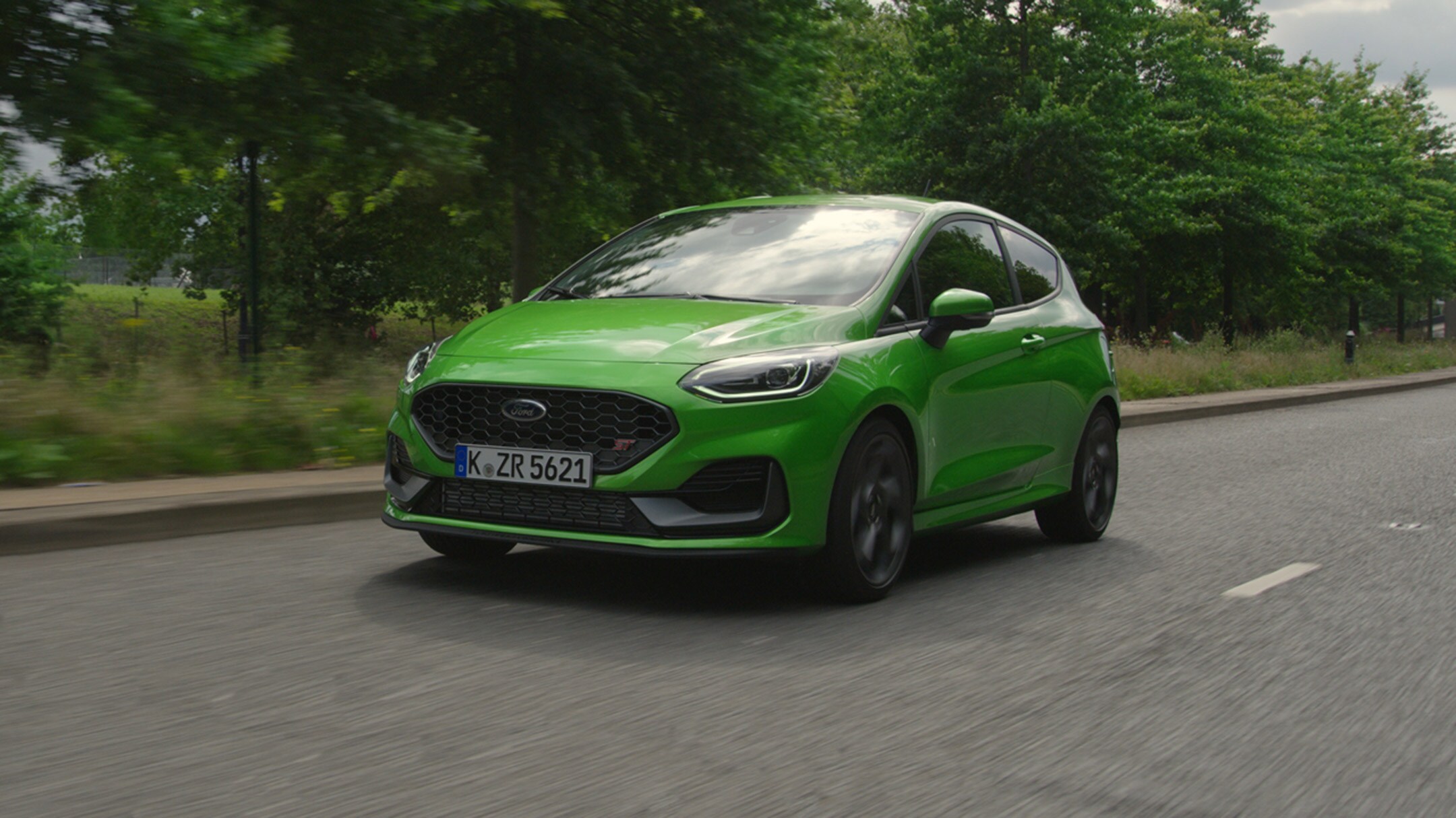 Ford Fiesta ST in Grün. Dreiviertelansicht, fährt in ländlicher Umgebung
