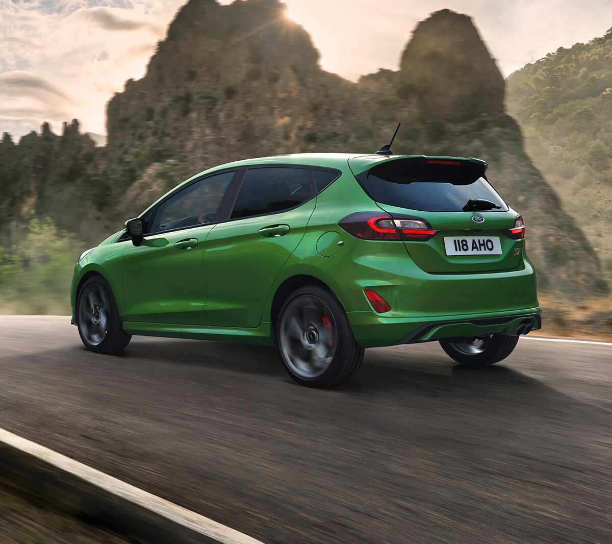 Ford Fiesta ST in Grün. Dreiviertelansicht, auf Straße in den Bergen fahrend.