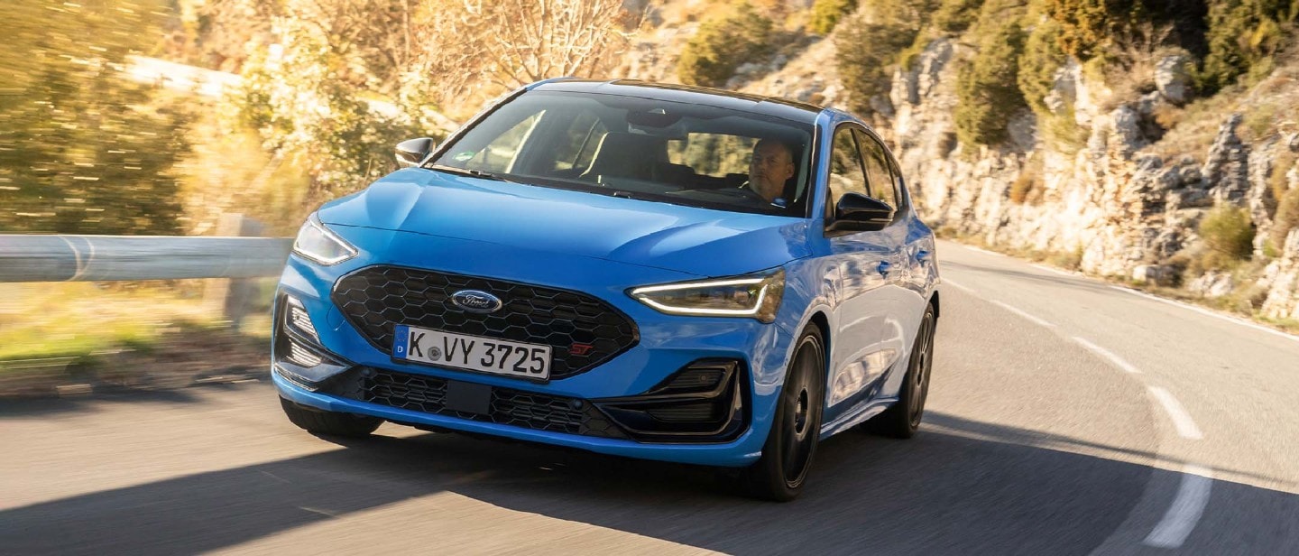 Ford Focus ST in Blau. Frontansicht, fahrend auf einer Straße.