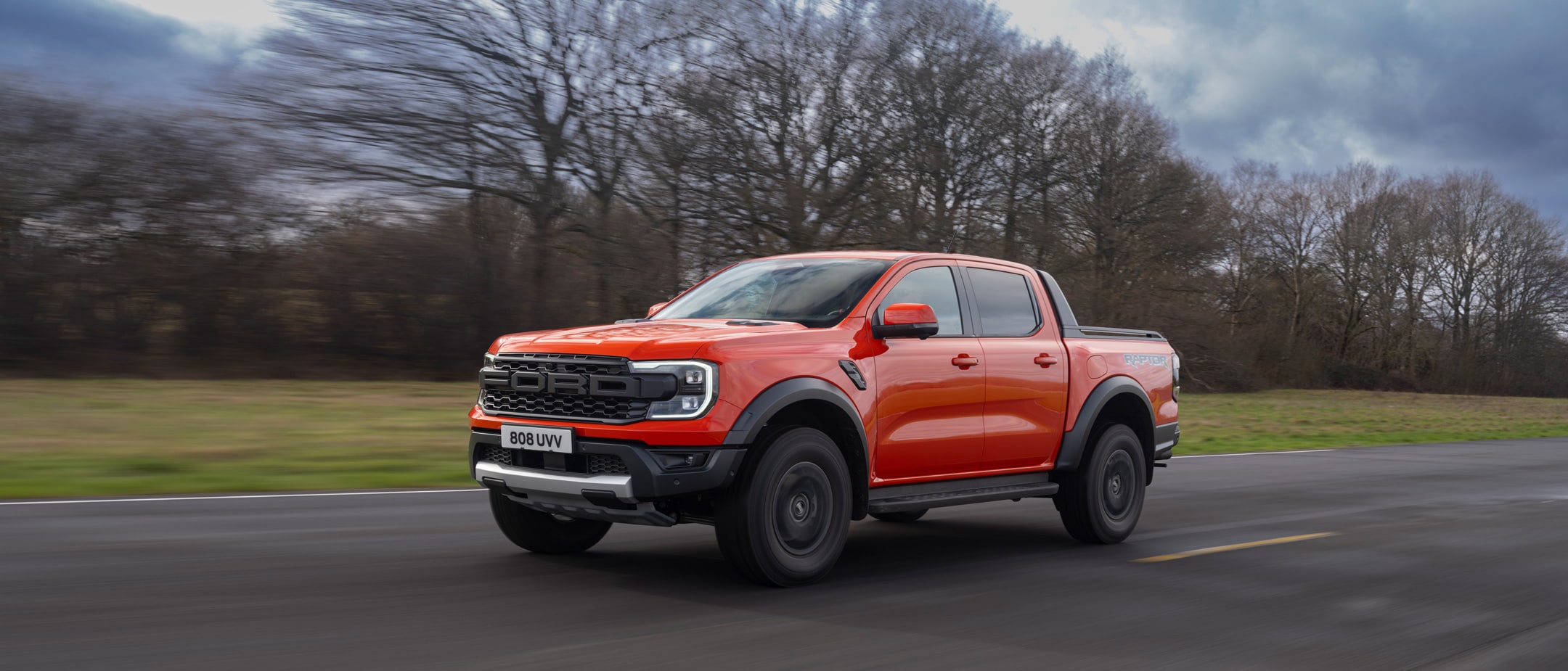 Ford Ranger Raptor in Rot. Dreiviertelansicht, fahrend auf einer Straße.