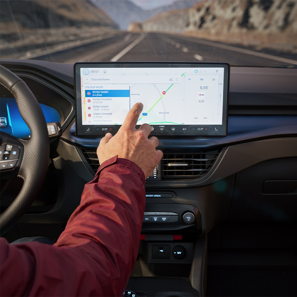 Ein Fahrer bedient Connected-Navigation auf dem Touchscreen im modernen Cockpit einer Ford BlueCruise Edition.