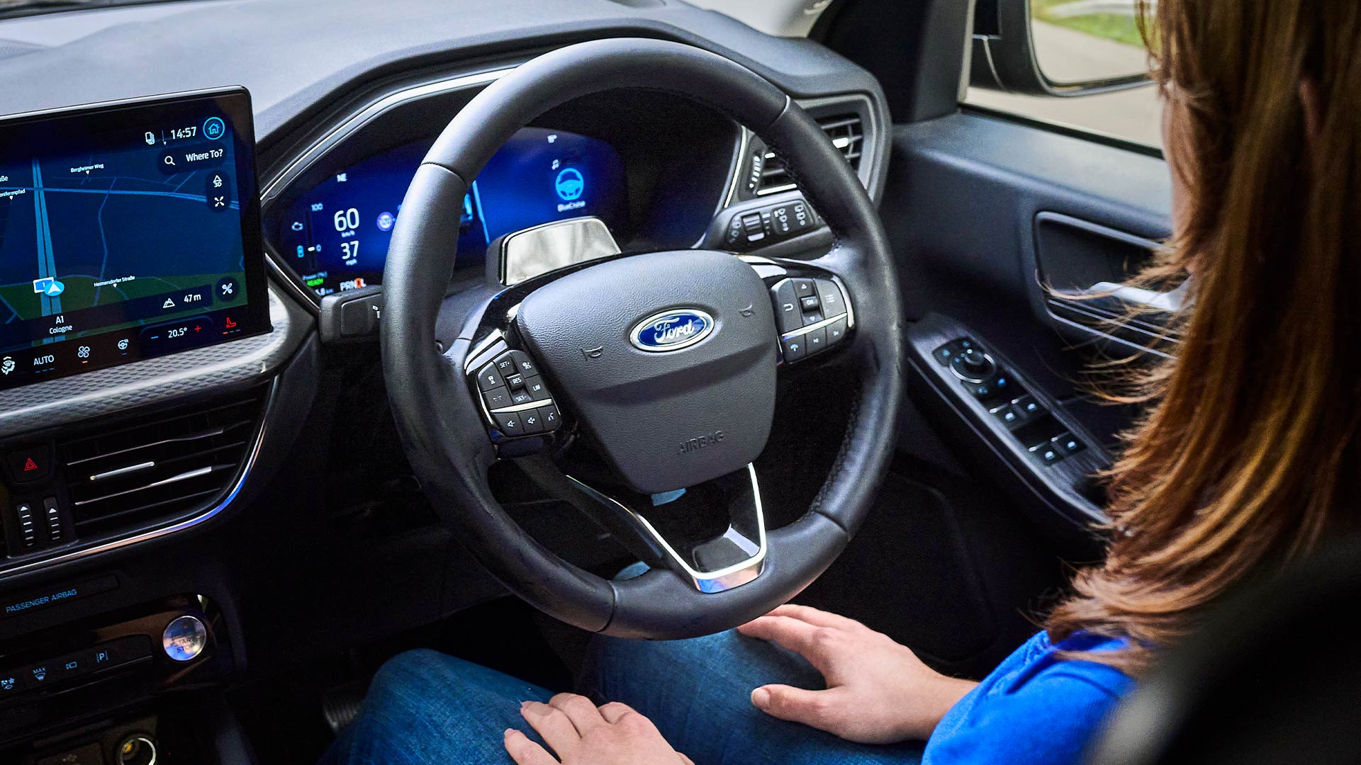 Ford Kuga Innenraum. Detailansicht Lenkrad und Touchscreen. Person sitzt am Fahrersitz.