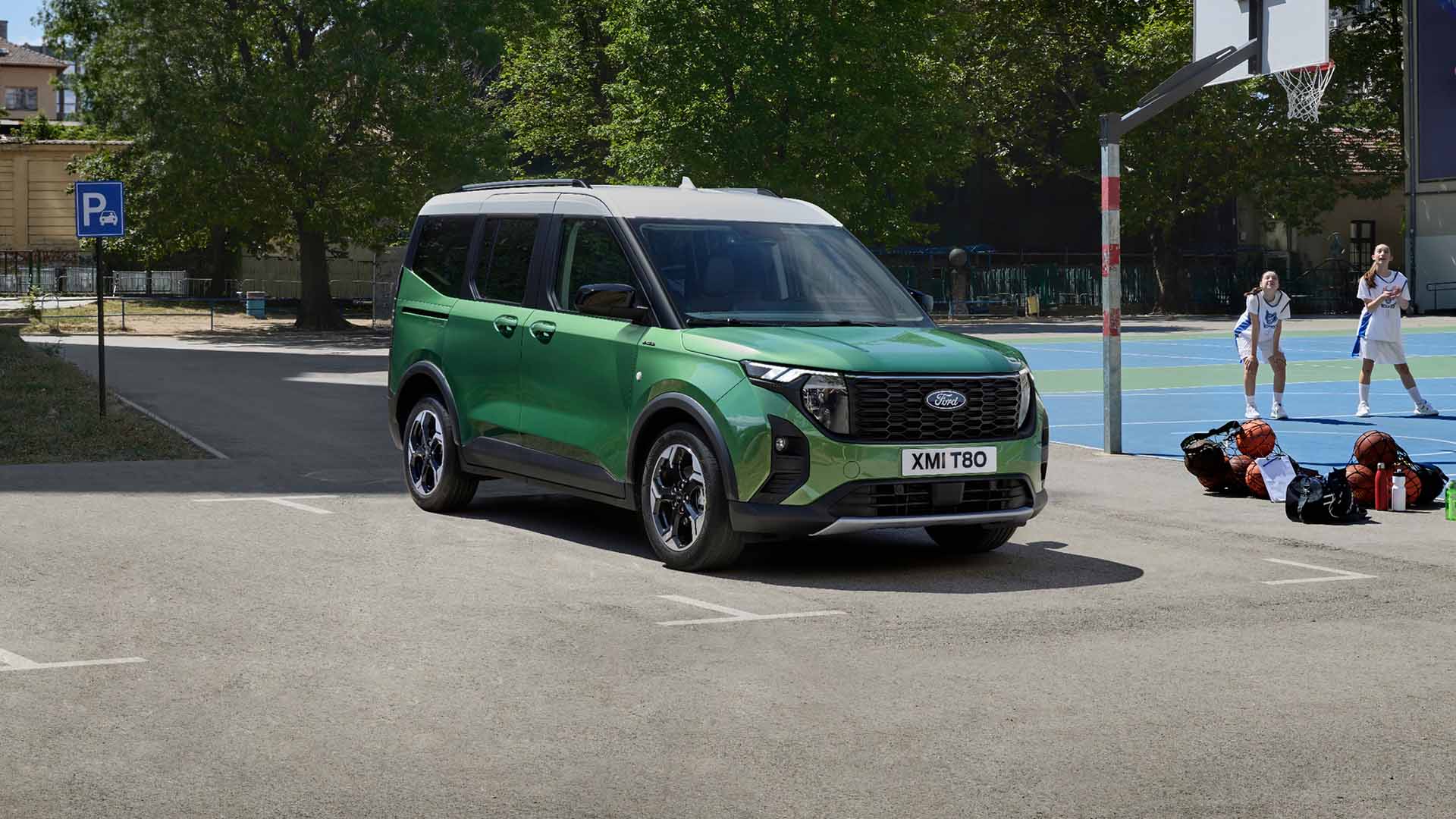 Ford Tourneo Courier in Grün. Dreiviertelansicht, auf einem Parkplatz mit Bäumen im Hintergrund.