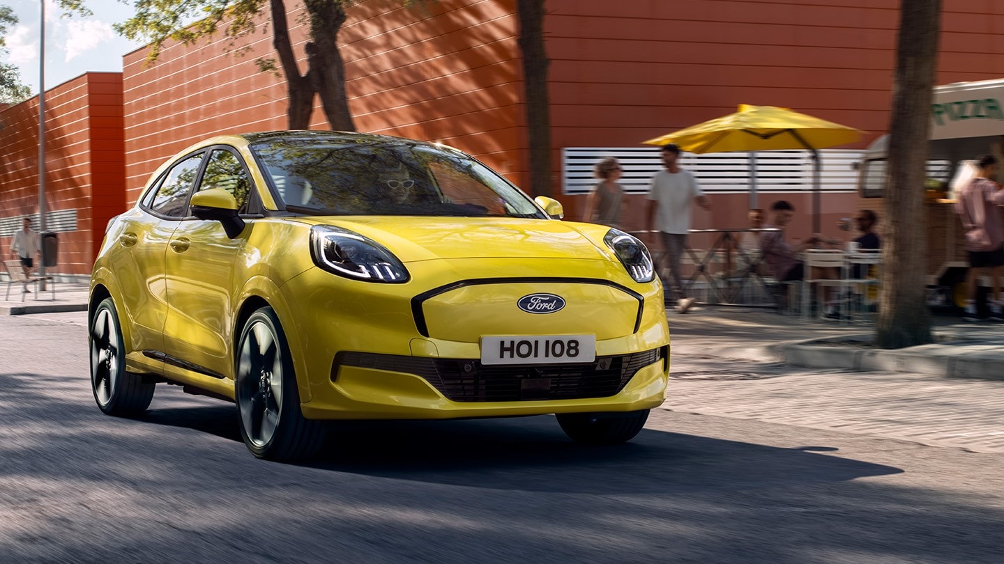 Ford Puma Gen-E in Gelb. Dreiviertelansicht, fährt auf einer Straße.